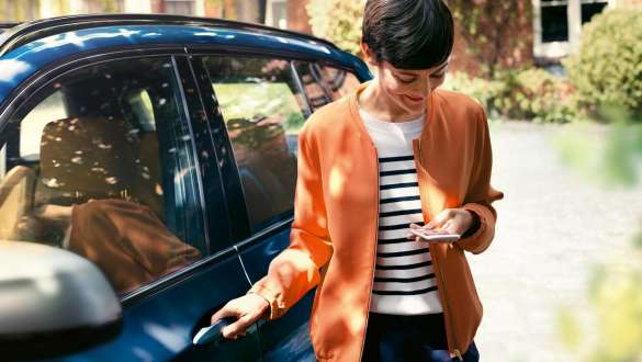 BMW Teleservices BMW Teleservices woman with smartphone next to BMW door