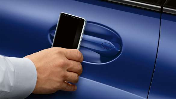 BMW Digital Key BMW 8 Series Coupé M Portimao Blue metallic G15 LCI Facelift 2022 hand holding smartphone in front of car door