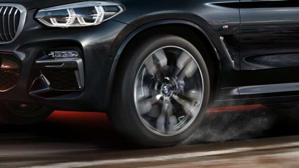 BMW X3 M40i, side view. BMW X3 M40i in Black Sapphire metallic, driving, exterior, side view with rotating light alloy wheel.