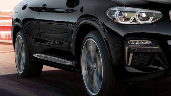 BMW X4 M40i, three-quarter side view. BMW X4 M40i in Black Sapphire metallic, driving, exterior, three-quarter side view with rotating light alloy wheels.