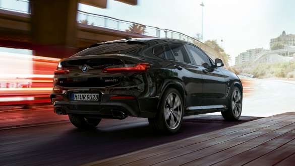 BMW X4 M40i, three-quarter rear view. BMW X4 M40i in Black Sapphire metallic, driving, exterior, three-quarter rear view with light strips.