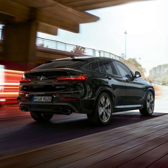 BMW X4 M40i in, three-quarter front view. BMW X4 M40i in Black Sapphire metallic, driving, exterior, three-quarter front view with light strips.