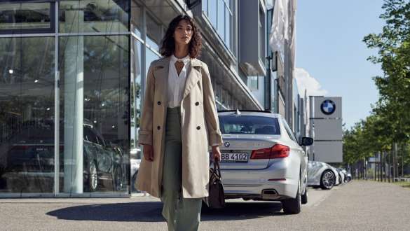 BMW Service Inclusive Woman in front of BMW car dealership