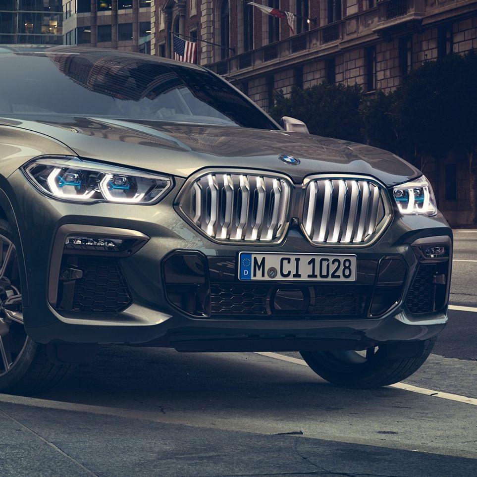 BMW X6 M50i SUV standing BMW X6 M50i SUV in three-quarter front perspective standing in front of an urban setting