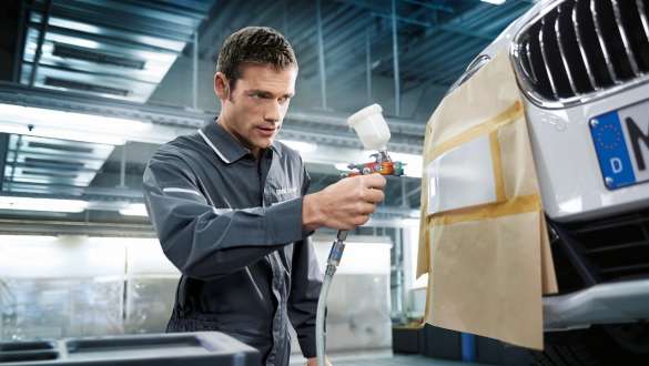 A varnisher spraying the front of a BMW. A varnisher spraying the front of a BMW.
