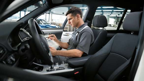 A BMW Service employee sitting on the passenger seat of a bmw whilst checking it. A BMW Service employee sitting on the passenger seat of a bmw whilst checking it.