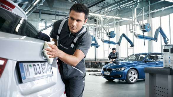 A BMW Service employee polishing the rear of a BMW. A BMW Service employee polishing the rear of a BMW.