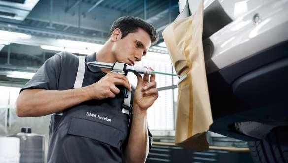 Un employé du service BMW répare le parechocs arrière d’une BMW. Un employé du service BMW répare le parechocs arrière d’une BMW.