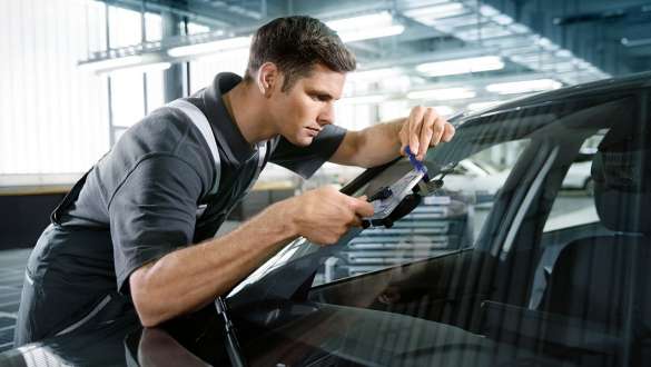 Un employé du service inspecte la vitre d’une BMW. Un employé du service inspecte la vitre d’une BMW.