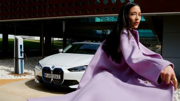 BMW Service Inclusive for electric vehicles BMW Service Inclusive woman stands in front of BMW i4 at charging station