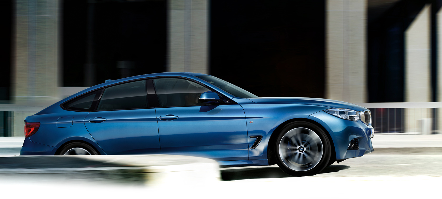 BMW 3 Series Gran Turismo in bright blue color driving from the tunnel. BMW 3 Series Gran Turismo in bright blue color driving from the tunnel.