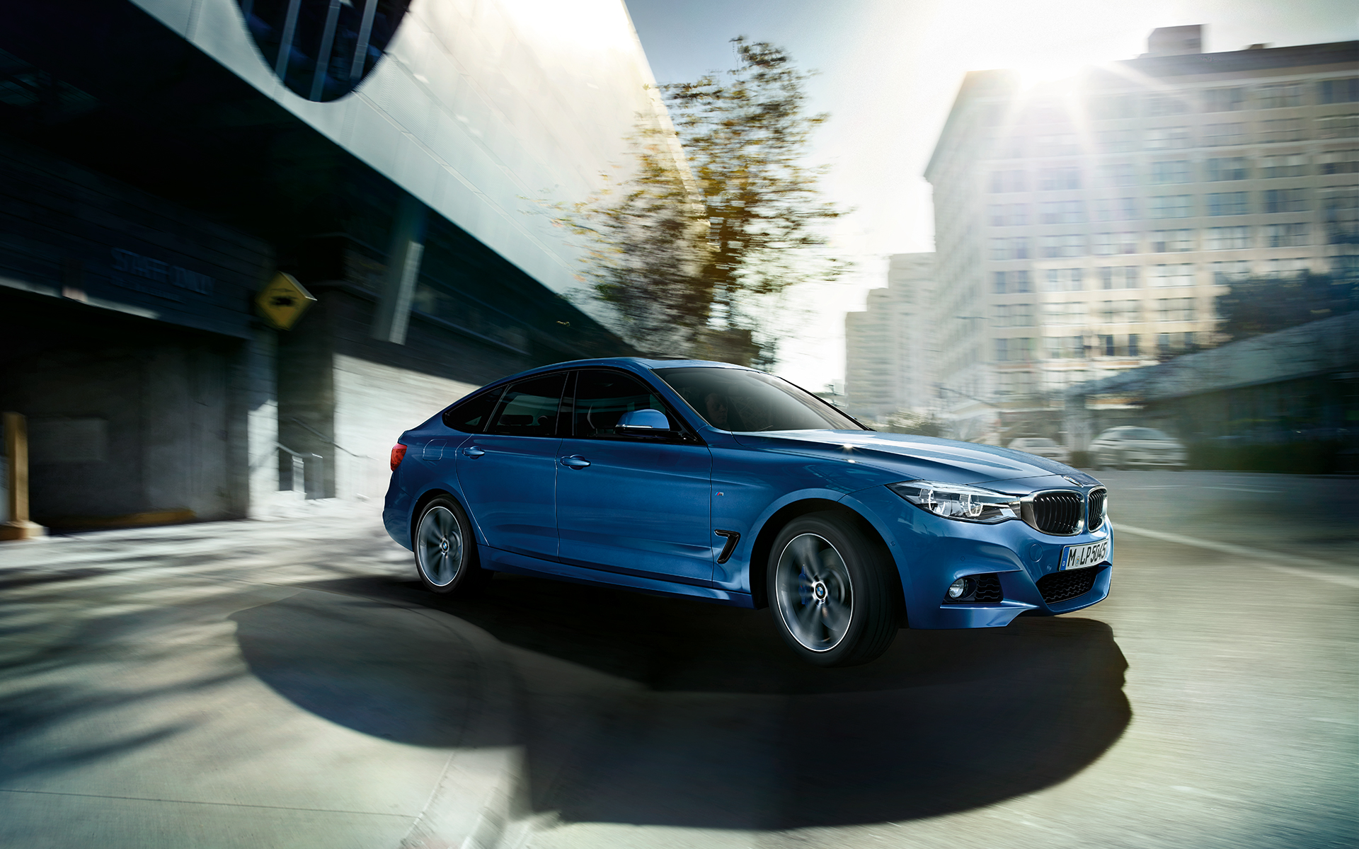 BMW 3 Series Gran Turismo - side view of metallic blue BMW in the sunny day. BMW 3 Series Gran Turismo - side view of metallic blue BMW in the sunny day.