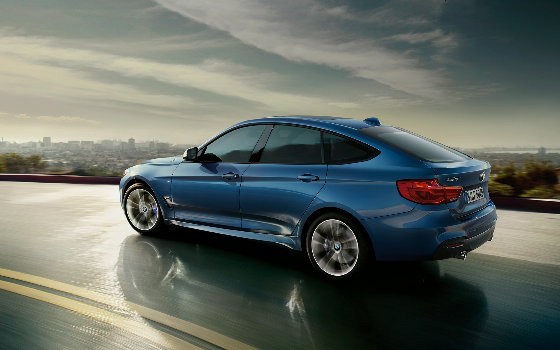 BMW 3 Series Gran Turismo: side view of car driving on highway with city scapes background. BMW 3 Series Gran Turismo: side view of car driving on highway with city scapes background.