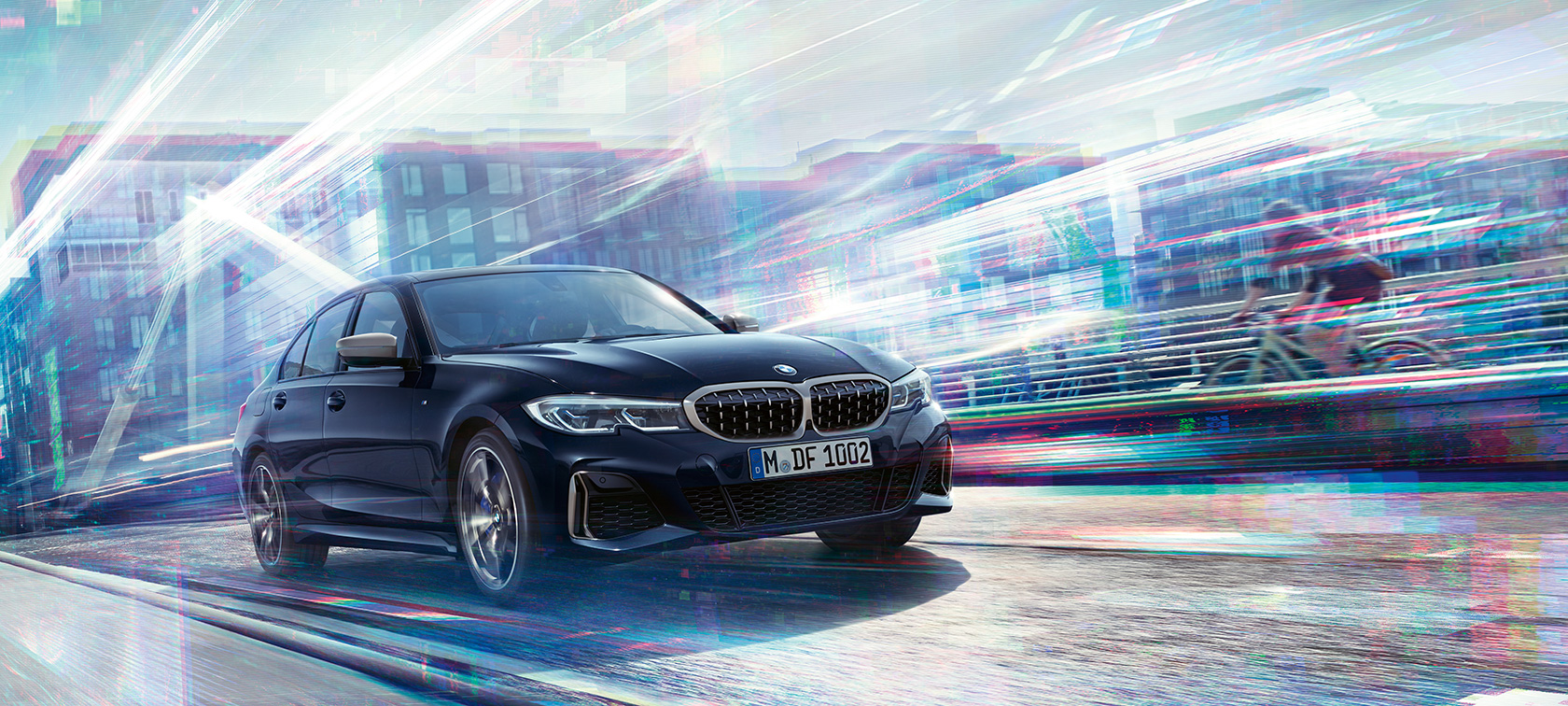 Lorem ipsum. Three-quarter side view of the BMW M340i xDrive driving on the road against an urban backround.