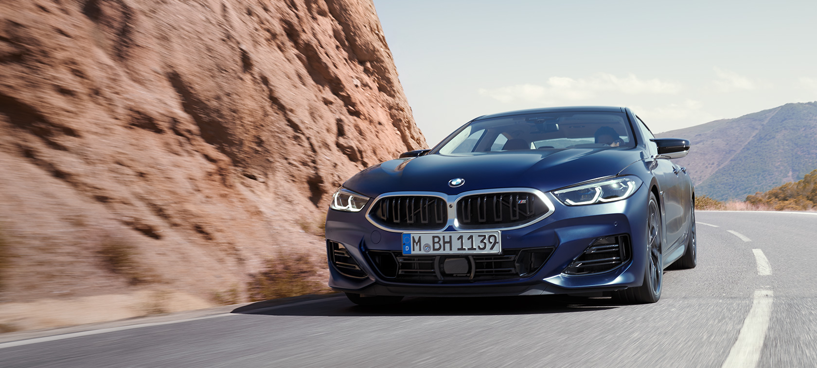 La BMW Série 8 Gran Coupé G16 LCI restylage 2022 BMW Individual Frozen Tansanitblau metallic, vue de trois quarts avant, en mouvement sur une route de montagne