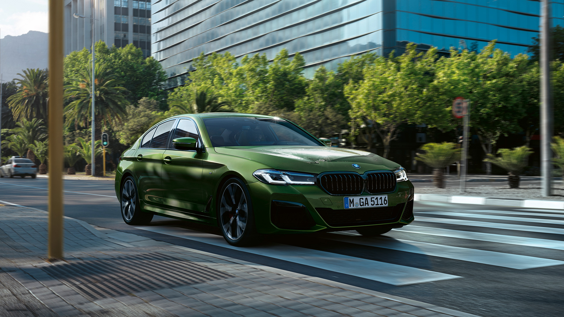 BMW M550i xDrive Berline G30 LCI restylage 2020 vue de trois quarts avant en conduite BMW M550i xDrive Berline G30 LCI restylage 2020 BMW Individual Verde Ermes metallic vue de trois quarts avant en conduite en ville