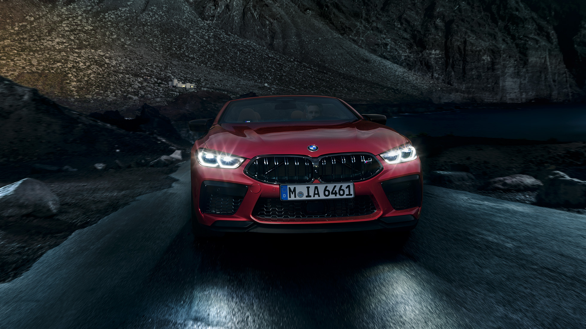 BMW M8 Compétition Cabrio, vue avant. BMW M8 Competition Cabrio en Motegi Rot metallic avec phares allumés, vue avant, en conduite de nuit.
