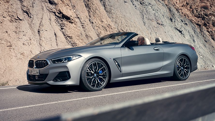 BMW M850i xDrive Convertible G14 LCI Facelift 2022 BMW Individual Frozen Pure Grey metallic three quarter front view driving in front of cliff face