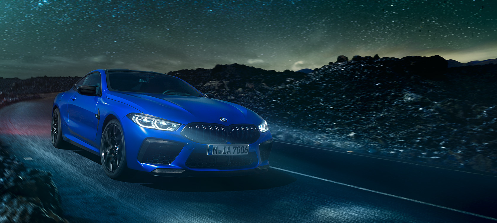 BMW M8 Competition Coupé, rear view. BMW M8 Competition Coupé, rear view, driving at night with full moon.