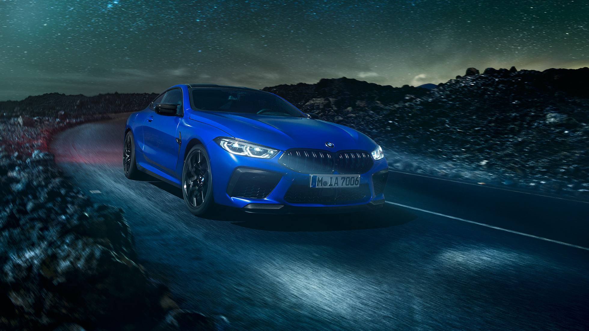 BMW M8 Competition Coupé, vue de profil. BMW M8 Competition Coupé en Marina Bay Blau metallic, prise de vue nocturne de profil à l’arrêt, devant un désert éclairé par la pleine lune.