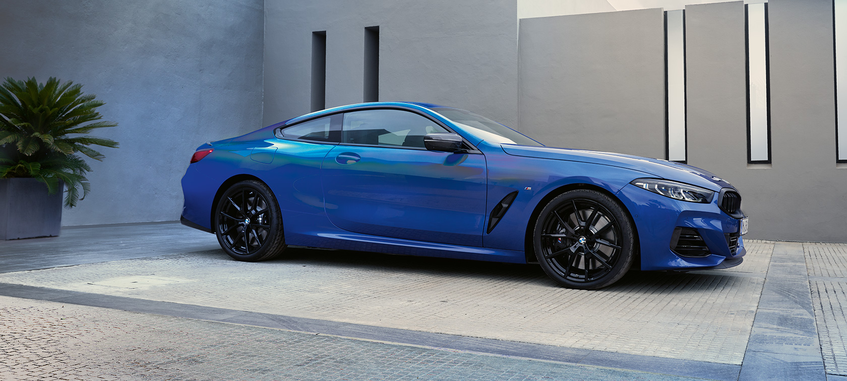 Vue de profil de BMW M850i xDrive Coupé G15 LCI restylage 2022 BMW M850i xDrive Coupé G15 LCI restylage 2022 M Portimao Blau metallic Vue latérale avant en stationnement devant bâtiment