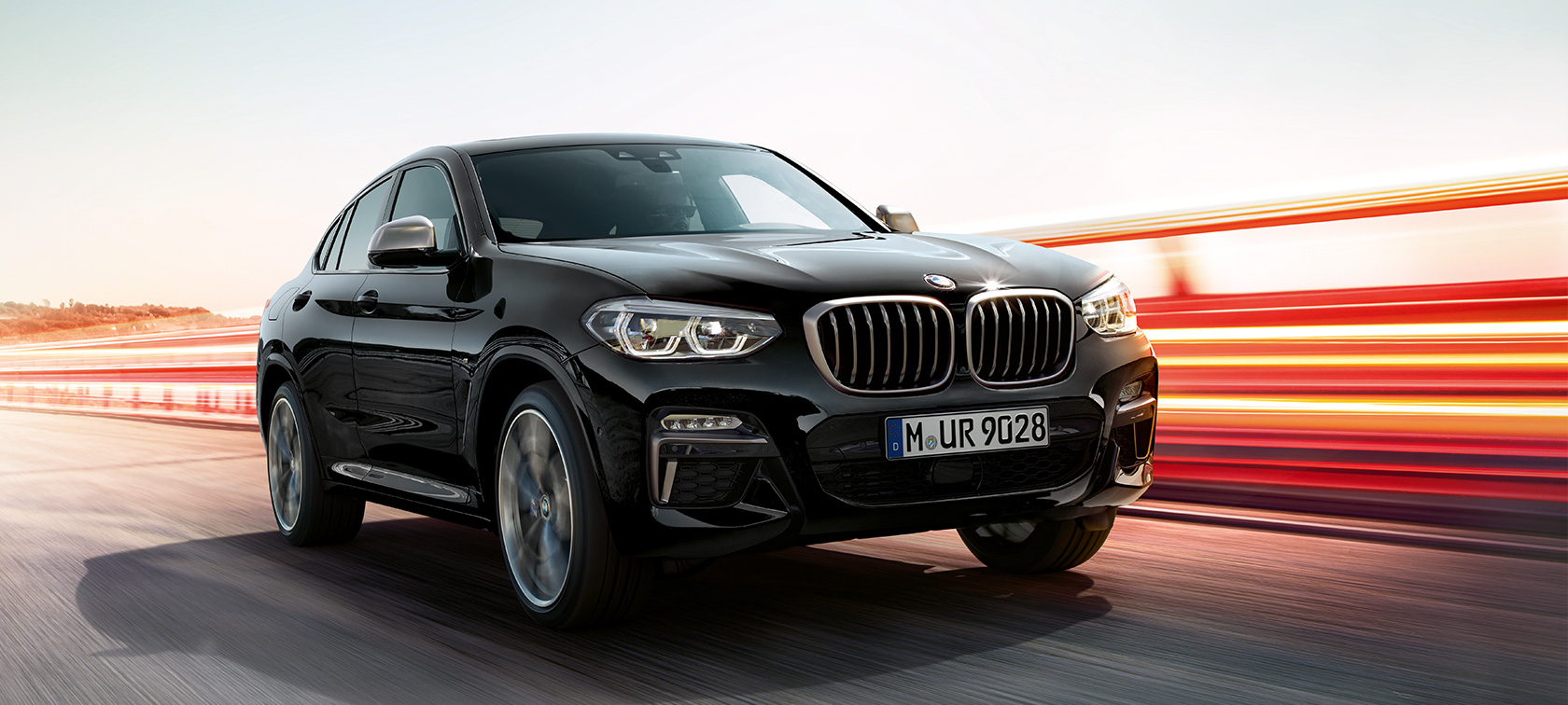 BMW X4 M40i, three-quarter front view, left side. BMW X4 M40i in Black Sapphire metallic, exterior, three-quarter front view, left side, with light strips.