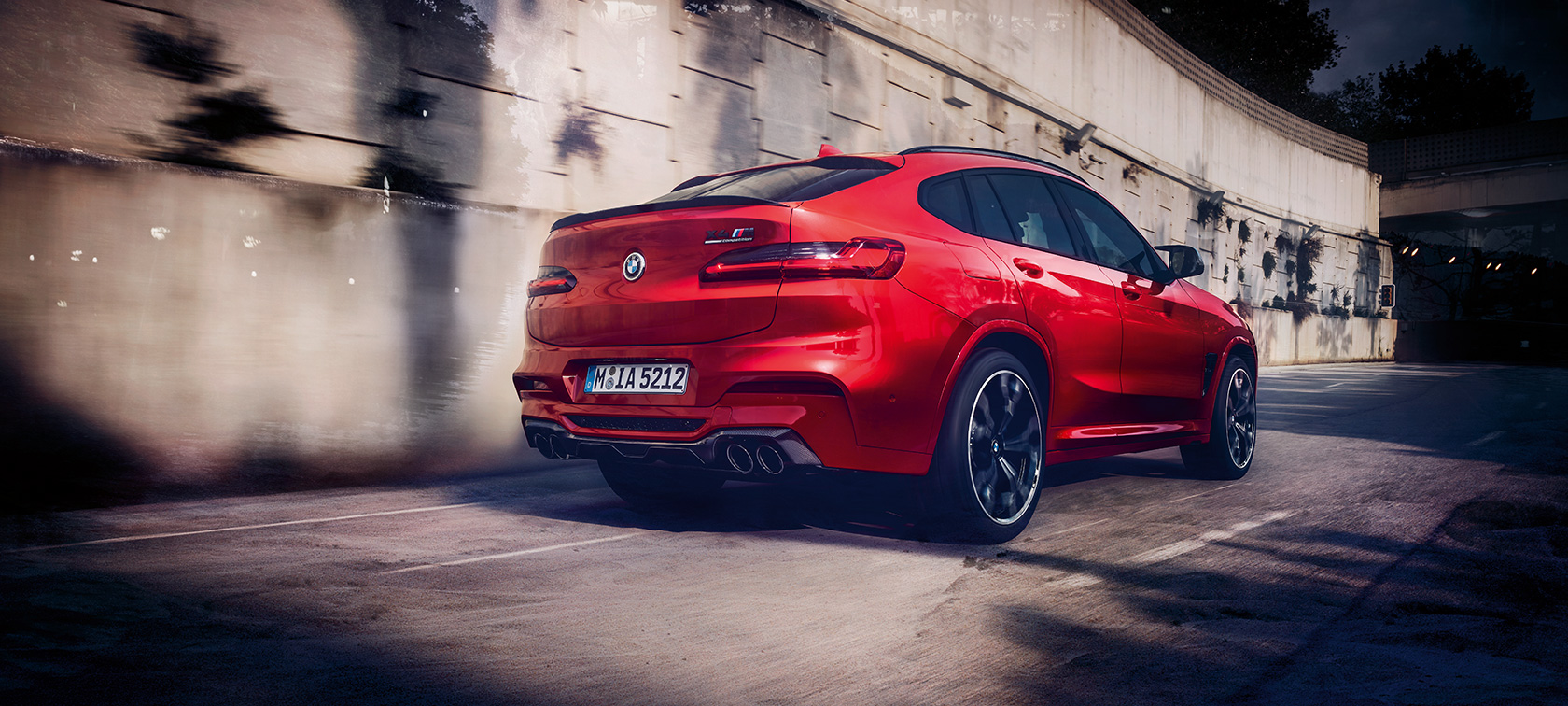 BMW X4 M Competition, three-quarter rear view. BMW X4 M Competition in Toronto Red metallic, driving, exterior, three-quarter rear view.