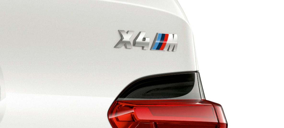 BMW X4 M, model designation. BMW X4 M in Alpine White, exterior, close-up view rear with model designation.