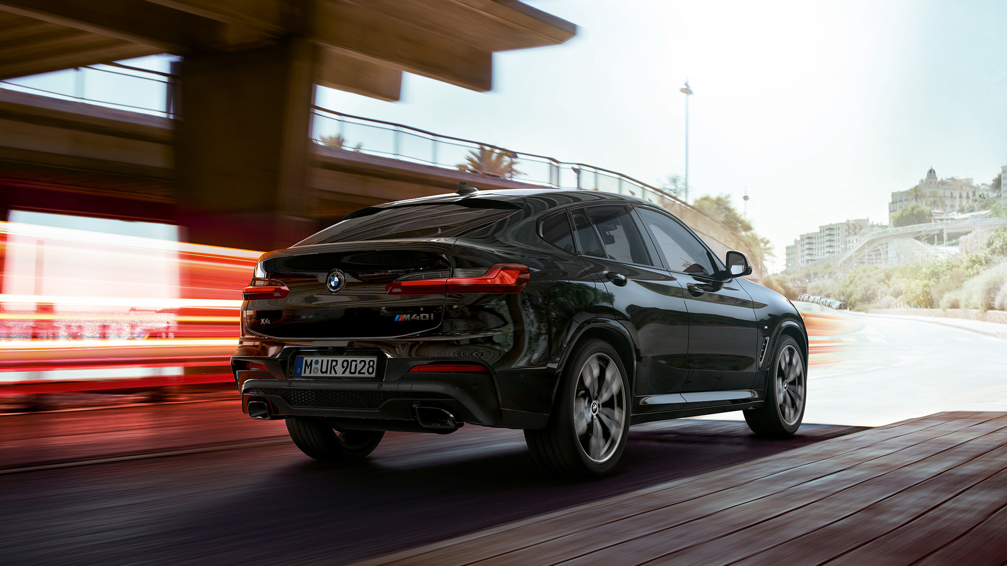 BMW X4 M40i in, three-quarter front view. BMW X4 M40i in Black Sapphire metallic, driving, exterior, three-quarter front view with light strips.