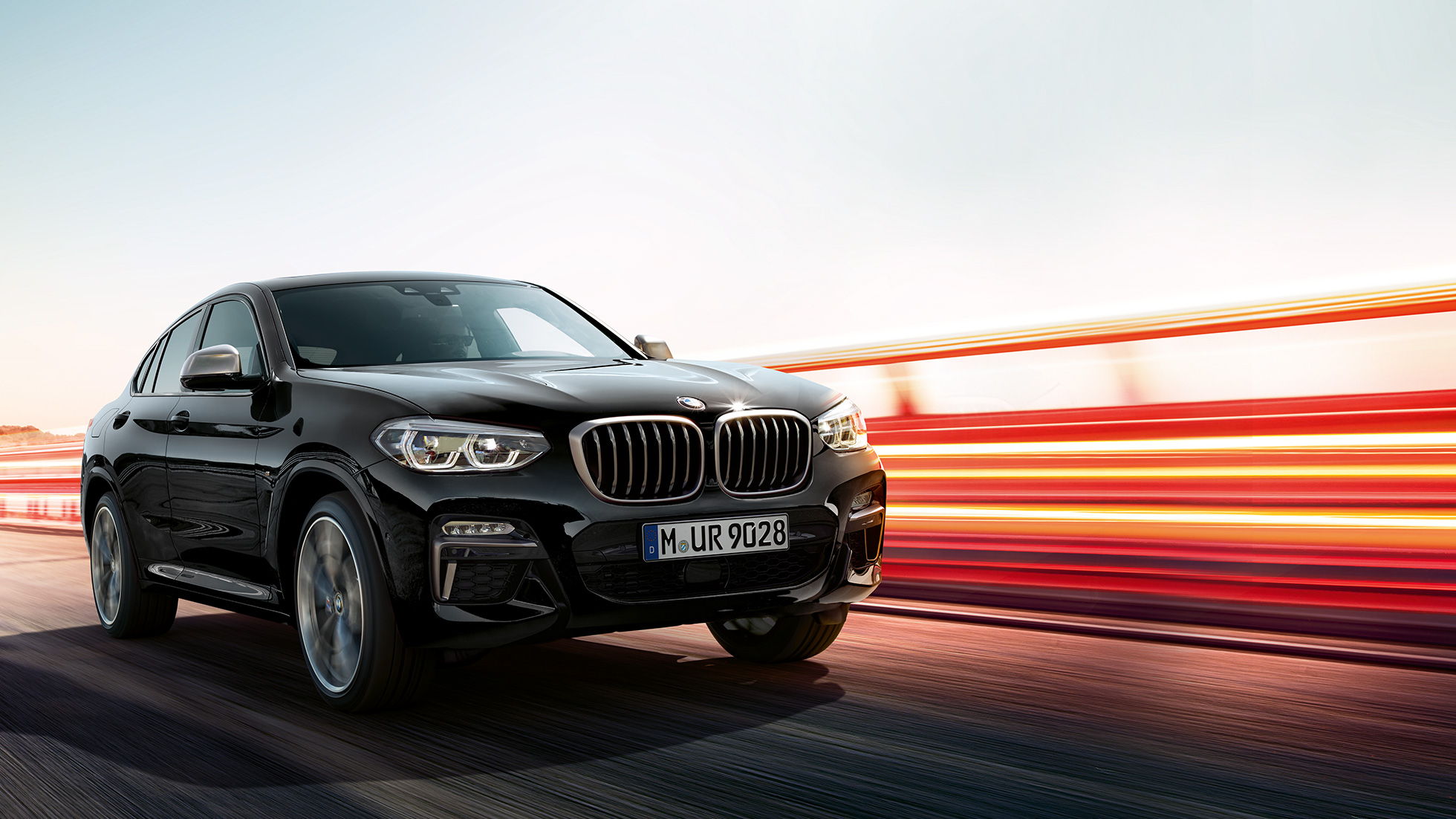 BMW X4 M40i, three-quarter rear view. BMW X4 M40i in Black Sapphire metallic, driving, exterior, three-quarter rear view with light strips.