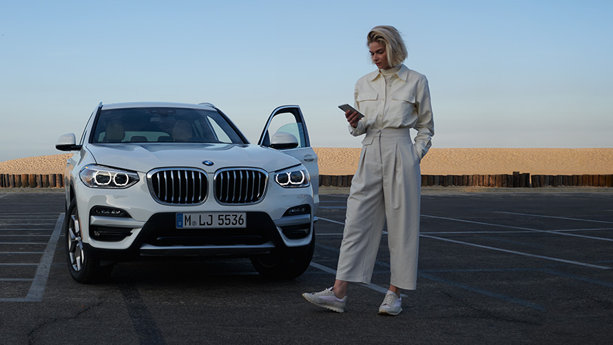 BMW X4 SUV G02 App Brochures 2021 BMW X4 SUV G02 App Brochures femme à côté d'une BMW 2021