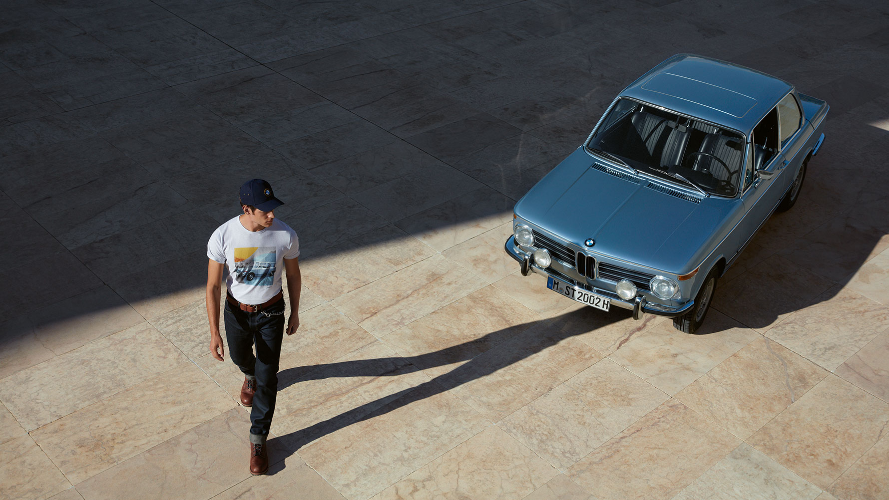 A man wearing a BMW Classic Men’s T-shirt is shown admiring a classic BMW. A man wearing a BMW Classic Men’s T-shirt is shown admiring a classic BMW.