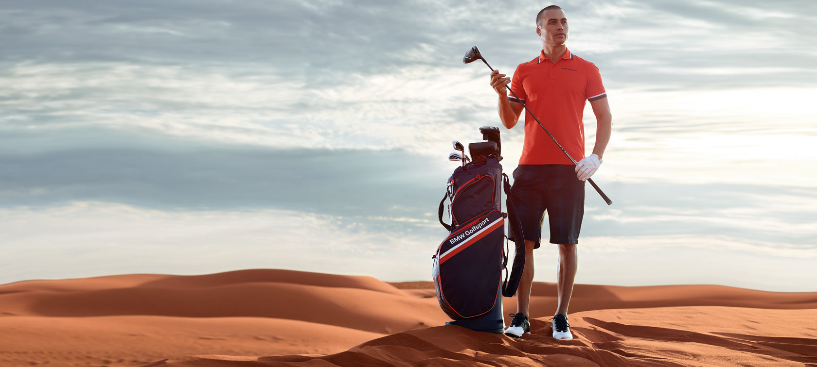 Homme en polo avec sac-chariot BMW Golfsport. Homme en polo avec sac-chariot BMW Golfsport.