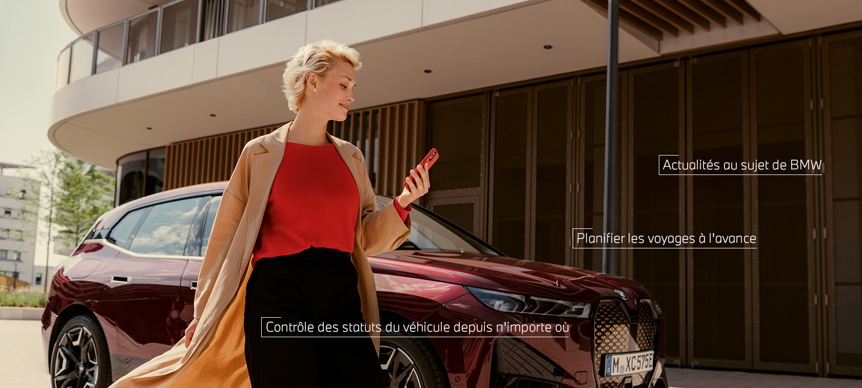 Une femme se tient devant une BMW X5 blanche et utilise l’App My BMW sur smartphone. Une femme se tient devant une BMW X5 blanche et utilise l’App My BMW sur smartphone.
