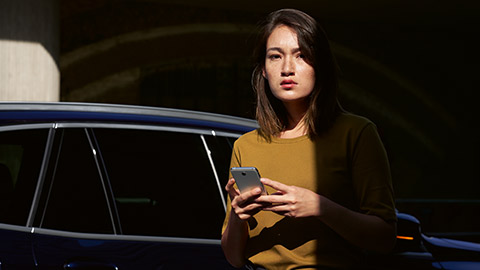 BMW ConnectedDrive Aperçu, femme avec smartphone dans les mains avec BMW en arrière-plan