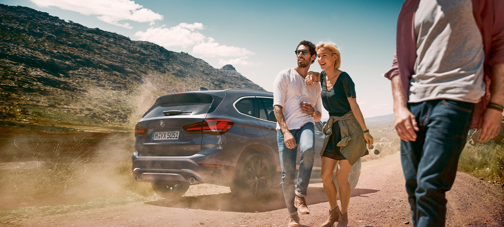 Parked BMW X1 Man and woman standing by a BMW X1 in the desert.