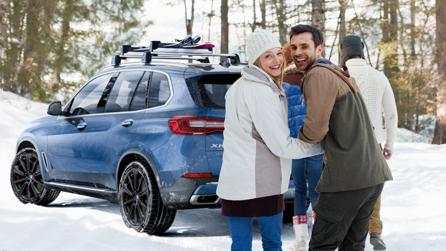 Group of friends in the snow around a BMW X3 Group of friends in the snow around a BMW X3