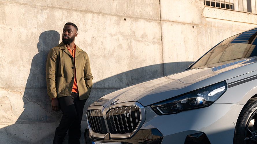 Man leaning on wall beside his BMW
