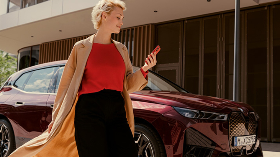 Woman walking away from BMW on phone.