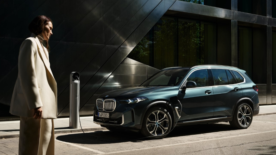 Woman standing beside BMW that is charging. 