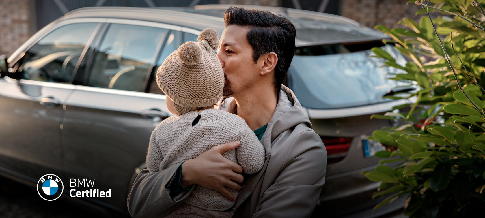 Man holding baby beside a BMW Man holding baby beside a BMW