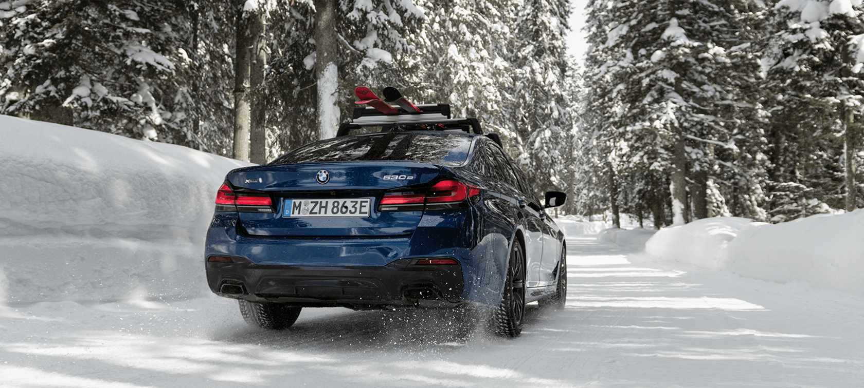 Accessoires BMW d’origine et Service BMW, automne-hiver Une femme et un homme rient dans la neige, devant une BMW