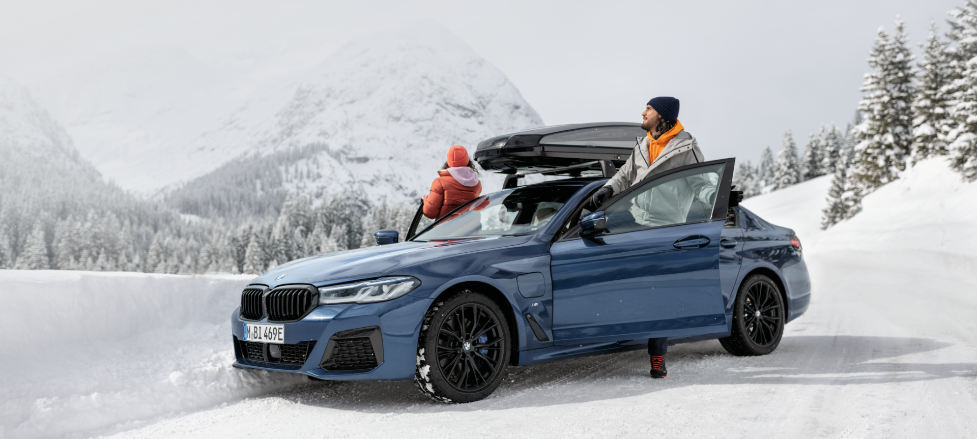 Accessoires automne-hiver BMW d’origine et gammes de services automne-hiver BMW Un homme et une femme enlacés devant une BMW