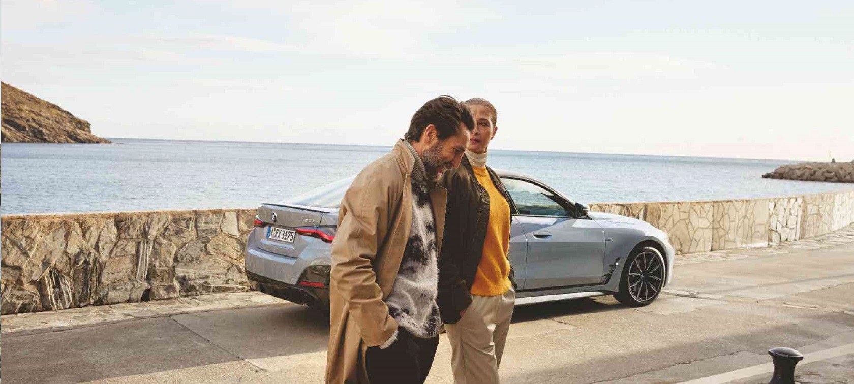 BMW three-quarter front view in front of mountain landscape with woman and man BMW Financial Services three-quarter front view in front of mountain landscape with woman and man